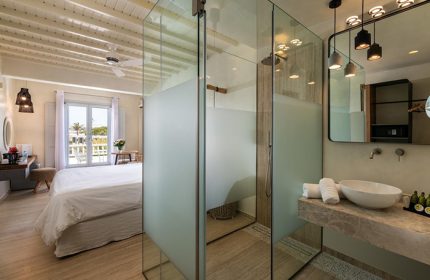 Mykonos honeymoon hotel suite bathroom with glass shower. Gay couple travel ideas in Mykonos Town. Poseidon Hotel suite interior.