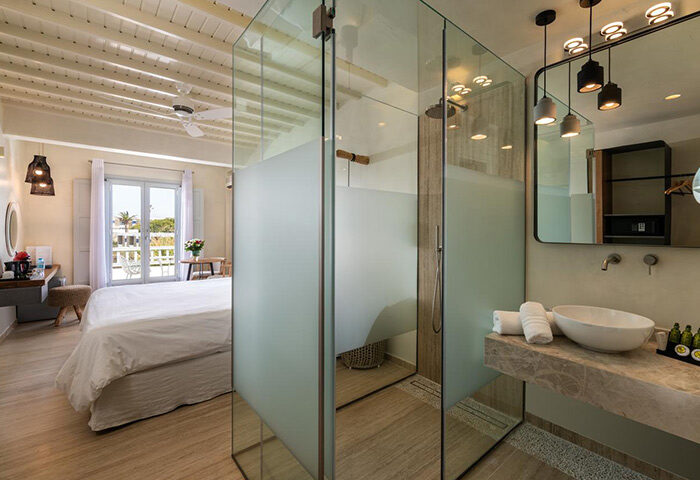 Mykonos honeymoon hotel suite bathroom with glass shower. Gay couple travel ideas in Mykonos Town. Poseidon Hotel suite interior.