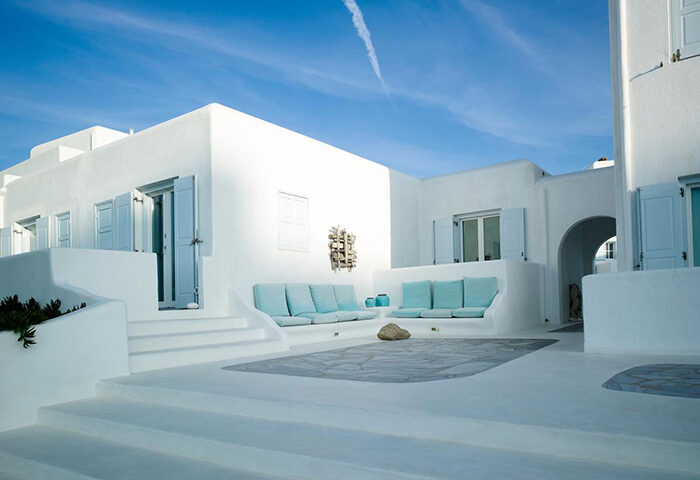 Mykonos Bay Resort & Villas outdoor lounge. Instagram-perfect gay hotel in Mykonos Town. Beachfront view, white buildings, blue accents.