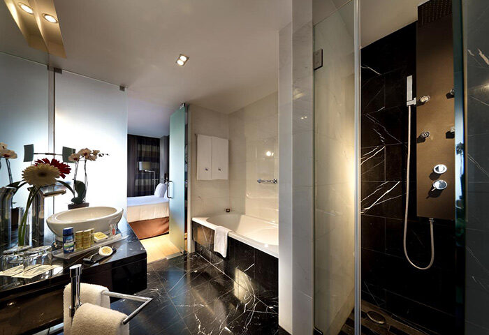 Eurostars Hotel das Letras, Lisbon: Modern bathroom with marble accents, glass shower, and view into the bedroom. Luxury gay hotel in city center.
