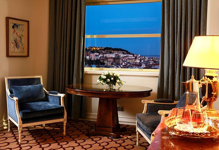 Tivoli Avenida Liberdade, a luxury gay hotel in Lisbon. Room interior with armchairs, table, and city view. Gay travel advice.