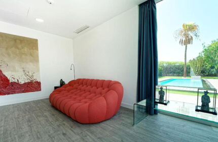 Seven Hotel & Wellness, gay men only: Red sofa in a room with a pool view. Most booked gay hotel in Gran Canaria. Modern interior design.