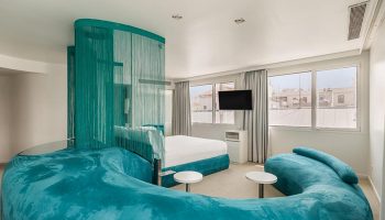 Room Mate Oscar, Madrid gay hotel. Turquoise sofa, bed, and beaded curtain. Modern design in Chueca, city center.