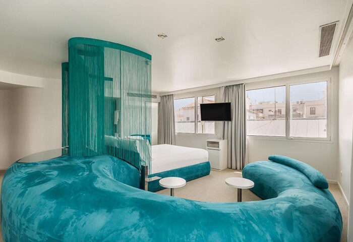 Room Mate Oscar, Madrid gay hotel. Turquoise sofa, bed, and beaded curtain. Modern design in Chueca, city center.