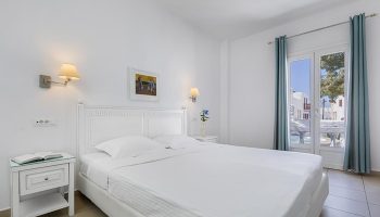 Carbonaki Hotel, Mykonos: White bedroom. A popular gay honeymoon hotel with a double bed, balcony view and bedside table.