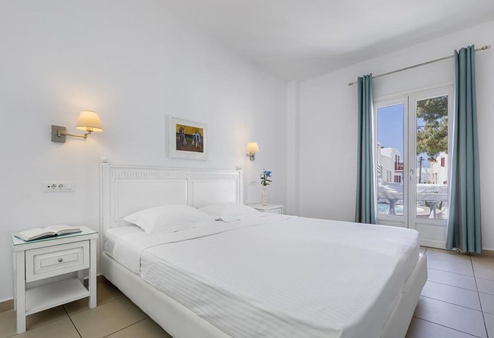 Carbonaki Hotel, Mykonos: White bedroom. A popular gay honeymoon hotel with a double bed, balcony view and bedside table.