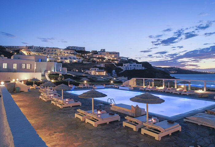 Mykonos Bay Resort pool at dusk. Gay hotel room for big groups in Mykonos Town beachfront. Popular gay travel destination in Greece.