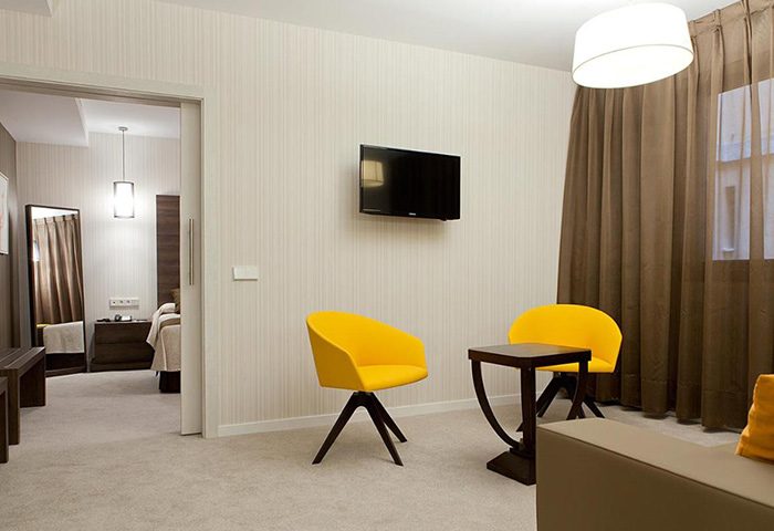 Hotel Liabeny, a top gay hotel in Madrid's gayborhood. Room interior with yellow chairs, TV, and modern design. Ideal for gay travel.