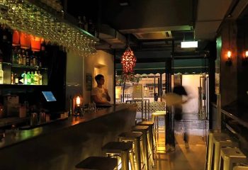 Time Bar Hong Kong cocktail bar. Interior view of the gayborhood bar with a man at the counter and stools. Best cocktail bar.