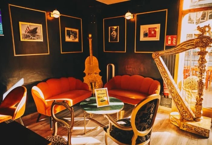 Interior of Titanic Bar, a gay bar in Barcelona. Ornate decor, seating, & a harp. A unique destination for gay men's travel.