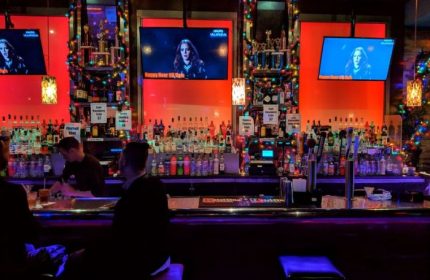 Toad Hall Bar in San Francisco, a gay bar. Bartender serving drinks, TVs, and colorful lights. A popular spot for gay men's travel.