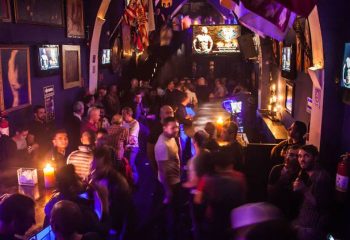 Tom's Leather Bar in Mexico: Gay men enjoy drinks and a party in a dimly lit, crowded space with TVs and candles. Gay travel advice.