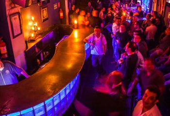 Tom's Leather Bar: Gay party scene in Mexico. Crowded gay bar with drinks, warm lighting, and a lively atmosphere. Gay travel advice.