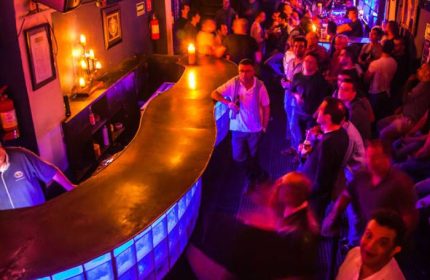 Tom's Leather Bar: Gay party scene in Mexico. Crowded gay bar with drinks, warm lighting, and a lively atmosphere. Gay travel advice.