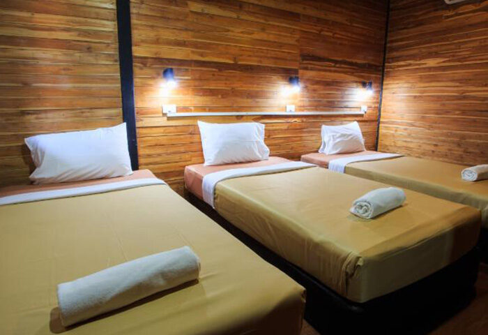 Ton Sai Beachfront Gay Hotel, Phi Phi Island: Three beds in a room with wooden walls, pillows, and rolled towels, perfect for gay travel.