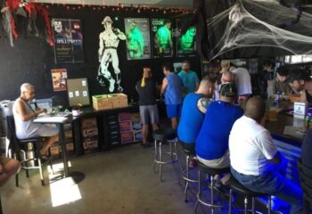 Tool Shed floor: Gay bar interior with patrons at the bar, Halloween decorations, and gay-themed art. Gay travel destination.