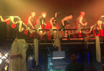 ToolBox Bar Phnom Penh: Performers on a decorated stage. Gay travel advice, nightlife scene. Red roses, fabric, and moody lighting. Cambodia.