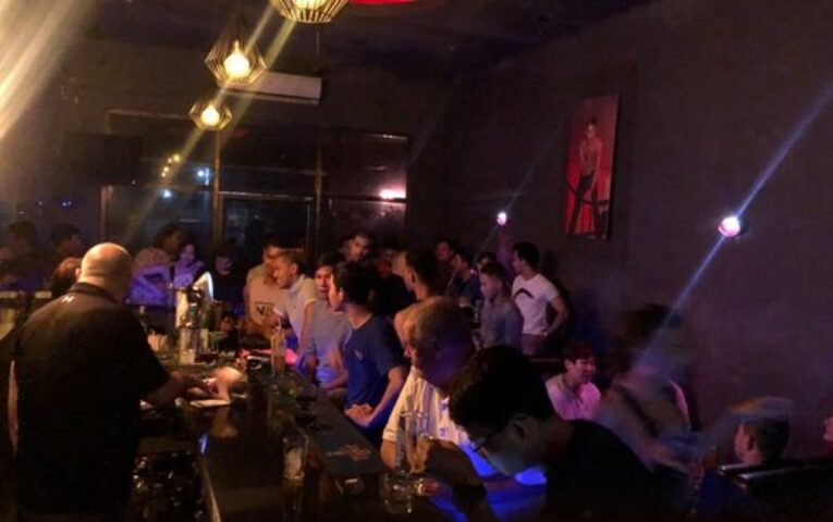 Busy ToolBox Bar in Phnom Penh. Gay bar scene with many men at the bar, enjoying drinks and socializing. Nightlife in Cambodia.