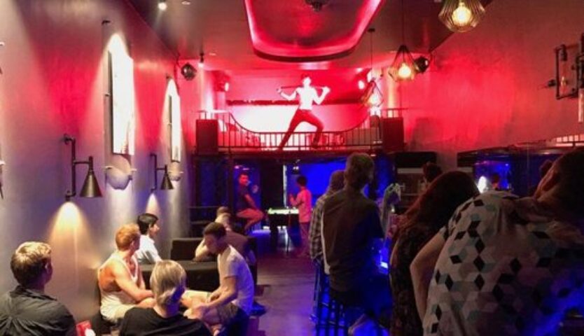 Toolbox Bar Phnom Penh: Gay bar interior with patrons & dancer on stage. Red lighting, pool table, & unique decor. Gay travel advice.