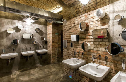 Czech Inn Hostel bathroom in Prague's Vinohrady gayborhood. Cool, chic design with brick walls, unique mirrors, and modern sinks.