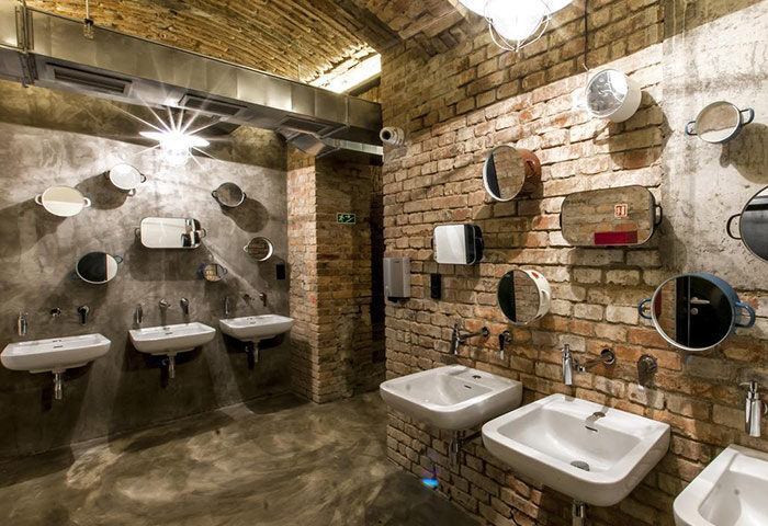 Czech Inn Hostel bathroom in Prague's Vinohrady gayborhood. Cool, chic design with brick walls, unique mirrors, and modern sinks.