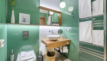 Mosaic House Design Hotel's cool bathroom in Prague's Old Town. Green glass walls, wood vanity, and modern fixtures. Gay-friendly hotel.
