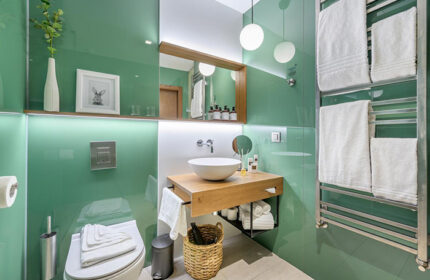 Mosaic House Design Hotel's cool bathroom in Prague's Old Town. Green glass walls, wood vanity, and modern fixtures. Gay-friendly hotel.