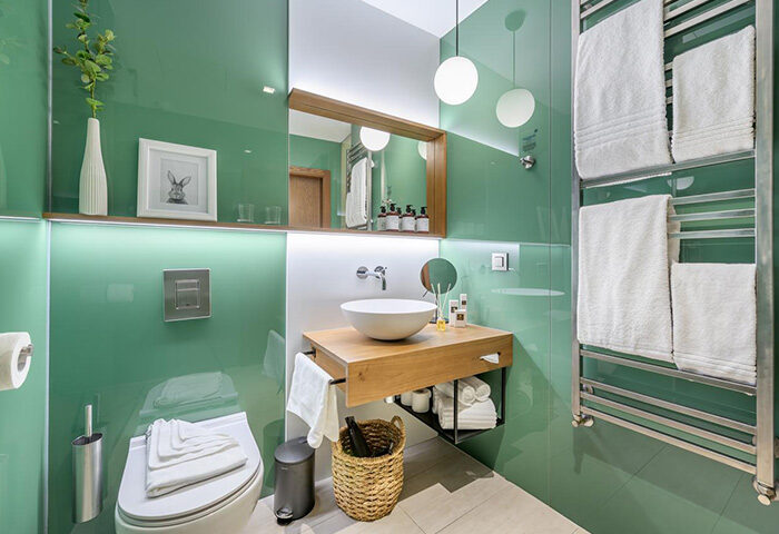 Mosaic House Design Hotel's cool bathroom in Prague's Old Town. Green glass walls, wood vanity, and modern fixtures. Gay-friendly hotel.