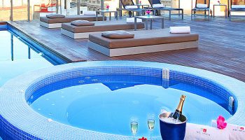 Rooftop view at Axel Hotel Barcelona, a gay adults-only hotel in Eixample. Features a jacuzzi, champagne, and lounge chairs. Urban Spa.