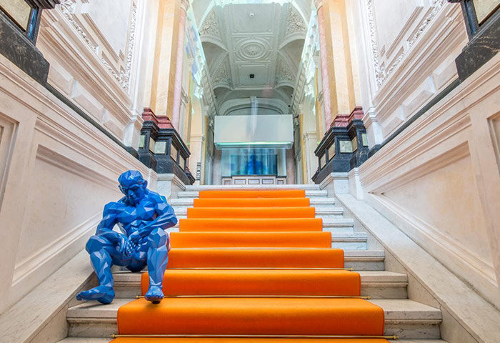 meetme23, top party hostel in Prague's gayborhood. Blue sculpture sits on orange-carpeted stairs in the grand lobby of this gay-friendly hotel.