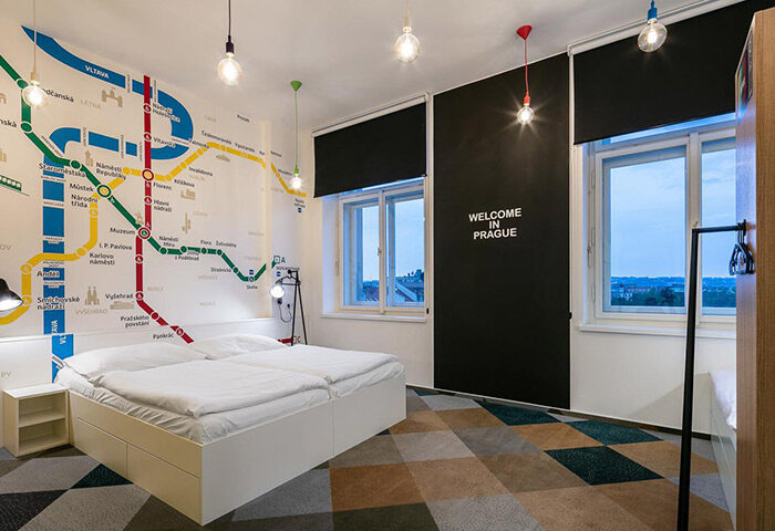 meetme23 party hostel room in Prague's gayborhood. Metro map mural, double bed, Welcome in Prague text. Top choice for gay travelers in Vinohrady.