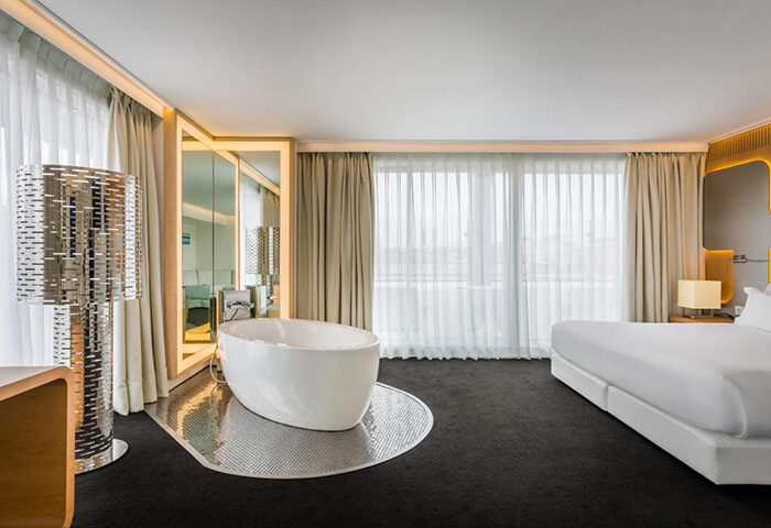 Room Mate Oscar, gay hotel Madrid. Modern room with bathtub, bed, and large windows. Top gay-friendly hotel with rooftop pool.