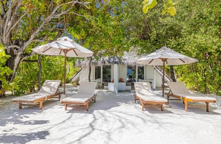 Beachfront at LUX* South Ari Atoll, Maldives. Gay resort with sunbeds and umbrellas for four people on white sand. Tropical luxury.