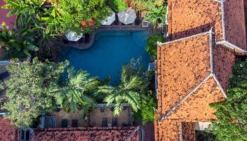 Aerial view of Rambutan Resort, a Cambodian-style gay hotel in Siem Reap, featuring an outdoor swimming pool and lush tropical gardens.
