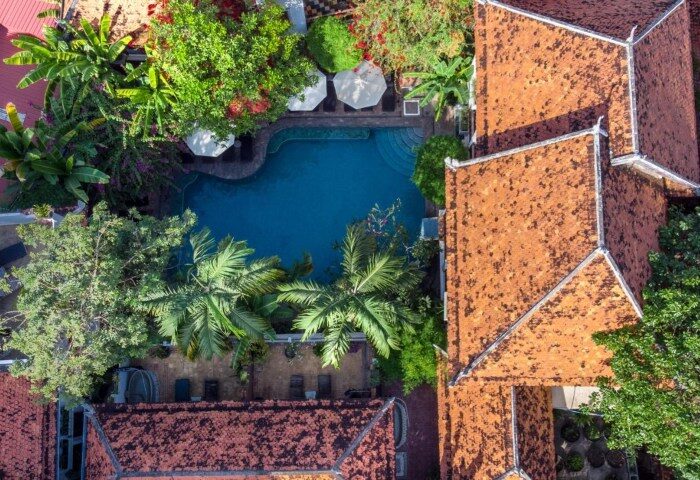 Aerial view of Rambutan Resort, a Cambodian-style gay hotel in Siem Reap, featuring an outdoor swimming pool and lush tropical gardens.