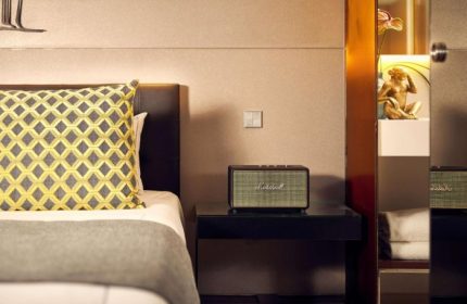 art'otel Amsterdam room detail. Bedside table with Marshall speaker, decorative pillow, and art piece. Top crazy art design at gay hotel.