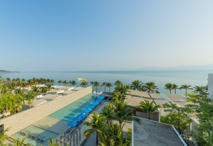 Explorar Koh Samui adults-only resort. Top gay beachfront resort view with pool, palm trees, and ocean. A serene gay travel destination.