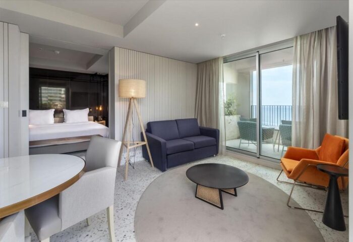 NEXT Hotel Madeira room interior. Gay honeymoon hotel in Portugal with balcony, sofa, and bed. Top gay beach destination.