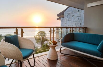 Double-Six Luxury Hotel Seminyak balcony view at sunset. Top gay-friendly beachfront hotel with stylish outdoor seating. Relax and enjoy Bali's beauty.