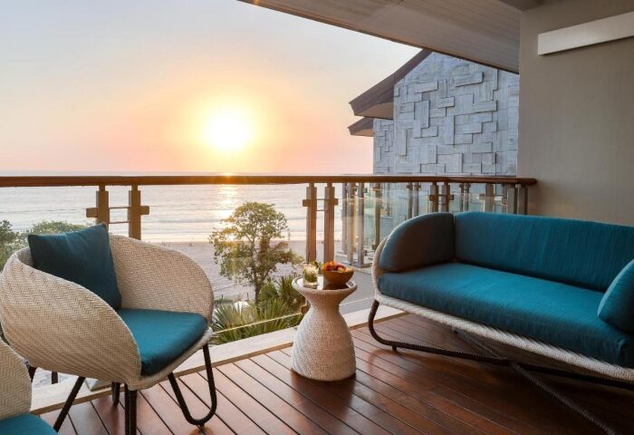 Double-Six Luxury Hotel Seminyak balcony view at sunset. Top gay-friendly beachfront hotel with stylish outdoor seating. Relax and enjoy Bali's beauty.