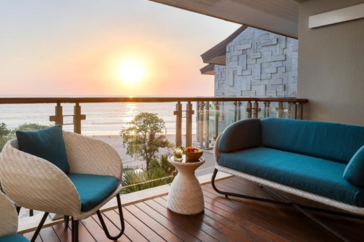 Double-Six Luxury Hotel Seminyak balcony view at sunset. Top gay-friendly beachfront hotel with stylish outdoor seating. Relax and enjoy Bali's beauty.