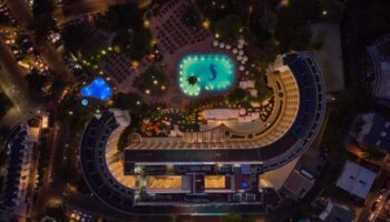 Aerial night view of Seaside Palm Beach, a top gay-friendly beachfront hotel near Gran Canaria's sand dunes, featuring illuminated pools.