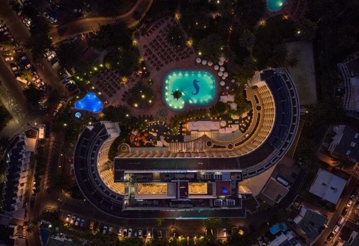 Aerial night view of Seaside Palm Beach, a top gay-friendly beachfront hotel near Gran Canaria's sand dunes, featuring illuminated pools.