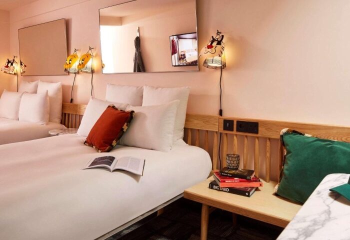 Mama Shelter London hotel room. Budget hotel in Shoreditch for gay men. Twin beds, cartoon lamps, and colorful pillows. Modern design.