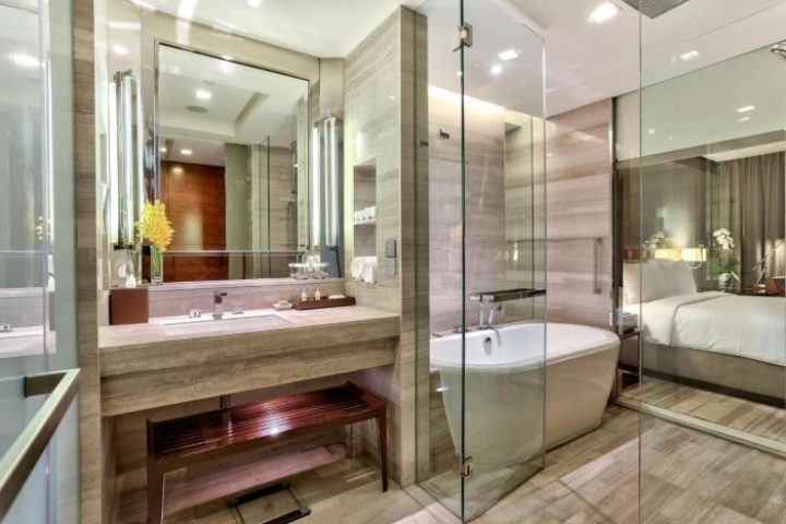 Bathroom at Hilton Sukhumvit Bangkok hotel, a top gay honeymoon destination. Features a tub, sink, mirror, & view into the bedroom.