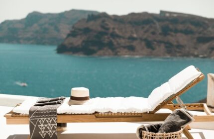 Armenaki Santorini gay honeymoon hotel. Beach view with sunbed and hat. Top gay travel destination. Relaxing beach hotels in Santorini.
