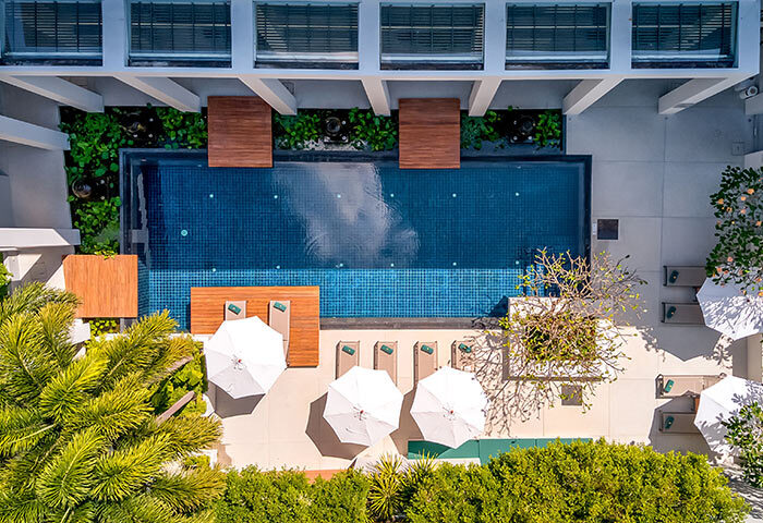 Outrigger Surin Beach Resort, Thailand. Top view of pool area, lounge chairs, umbrellas. Gay honeymoon hotel in Phuket. TikTok worthy.