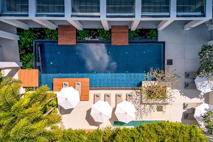 Outrigger Surin Beach Resort, Thailand. Top view of pool area, lounge chairs, umbrellas. Gay honeymoon hotel in Phuket. TikTok worthy.