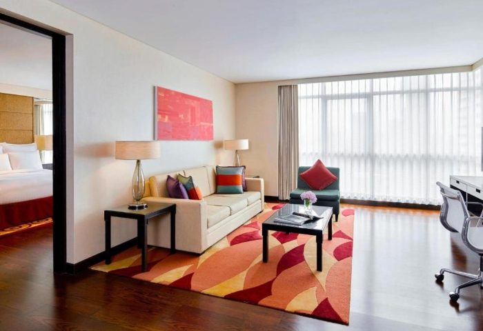 Sathorn Vista, Bangkok - Marriott Executive Apartments suite. Living area with sofa, chair, and colorful rug. Gay honeymoon hotel, city centre.