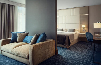 Hotel Kings Court, Prague. Luxurious suite with a plush sofa and a view into the bedroom, perfect for a gay honeymoon in Old Town.